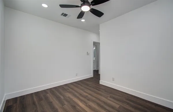 an empty room with wooden floor ceiling fan and window