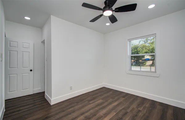 an empty room with wooden floor a ceiling fan and windows