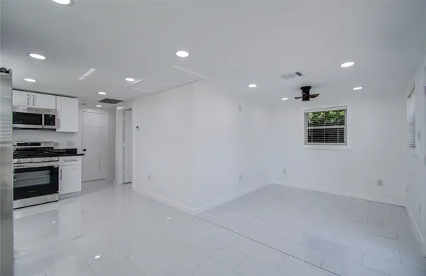 an empty room with kitchen view and a window