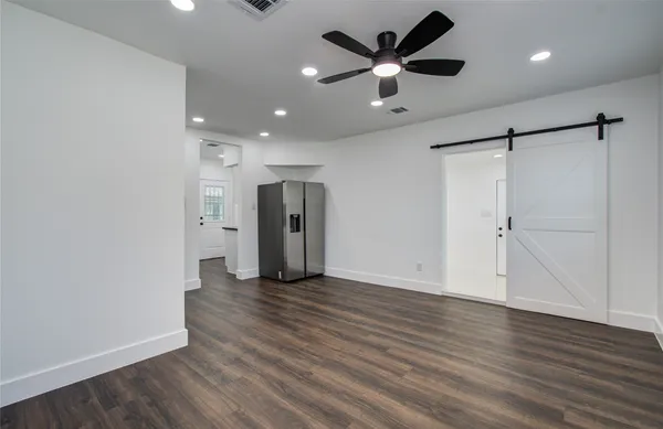 an empty room with wooden floor and a ceiling fan