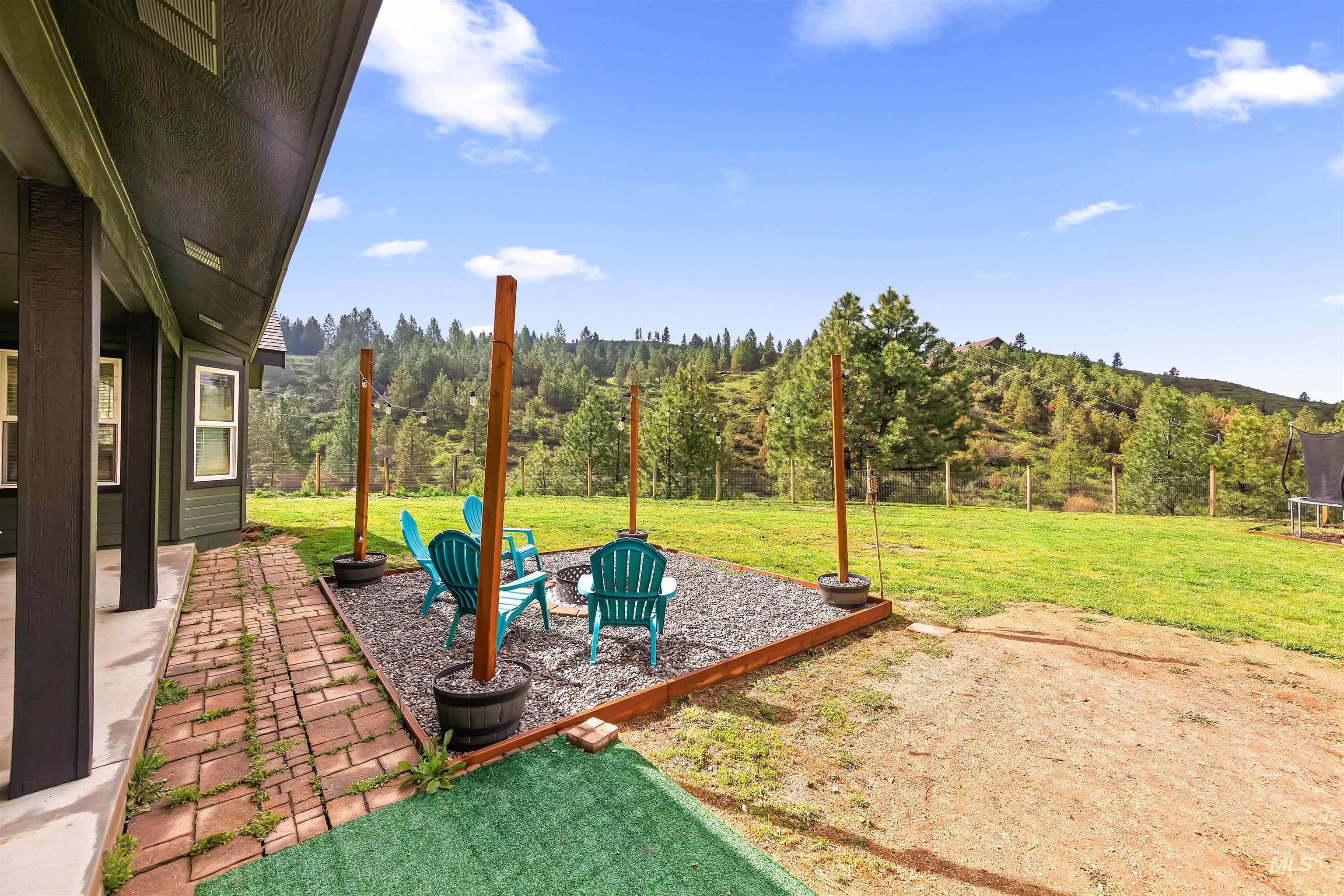 4 Round Up Circle Boise, ID 83716 - Photo 40 of 47 Outdoor patio area with gravel ground cover and a raised border, featuring a brick walkway, an expansive lawn, and distant treed hills