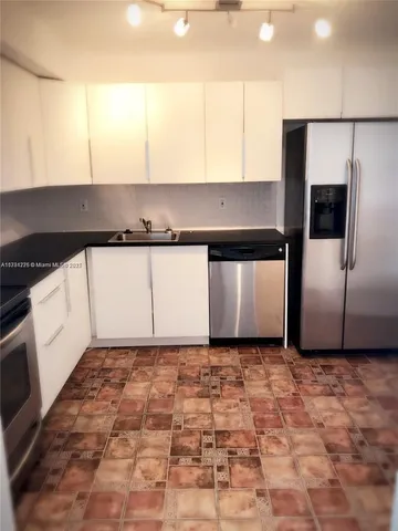 a kitchen with a sink a refrigerator and cabinets