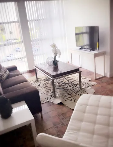 a living room with furniture a flat screen tv and a window