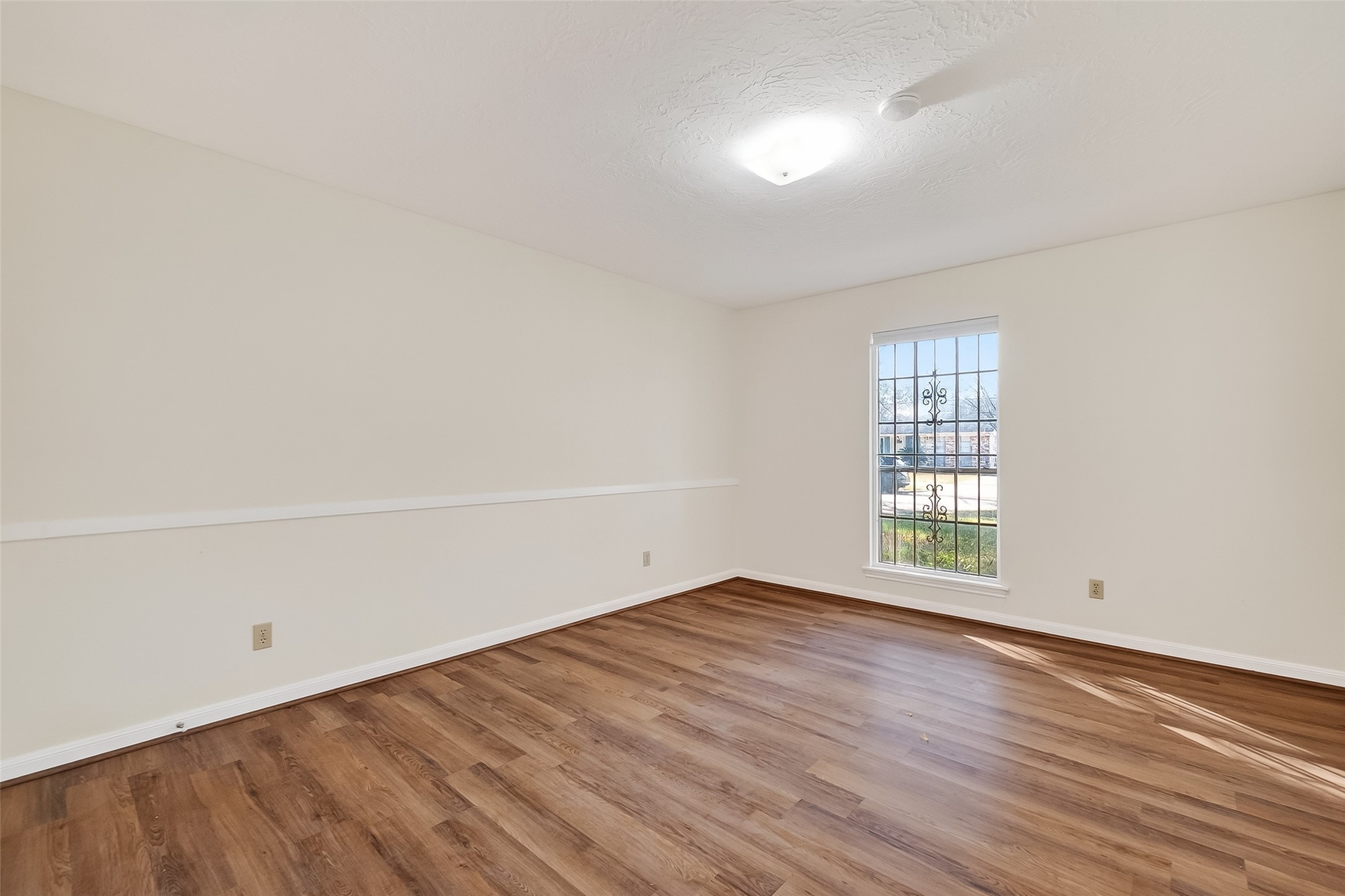9218 Rowan Lane Houston, TX 77036 - Photo 21 of 32 an empty room with wooden floor and windows