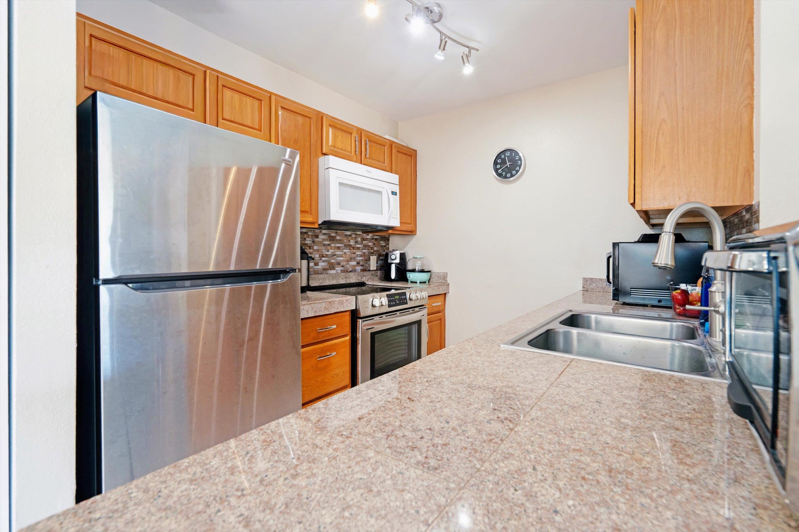 140 Uwapo Road, Unit 19105 Kihei, HI 96753 - Photo 6 of 42 a kitchen with stainless steel appliances granite countertop a refrigerator and a sink
