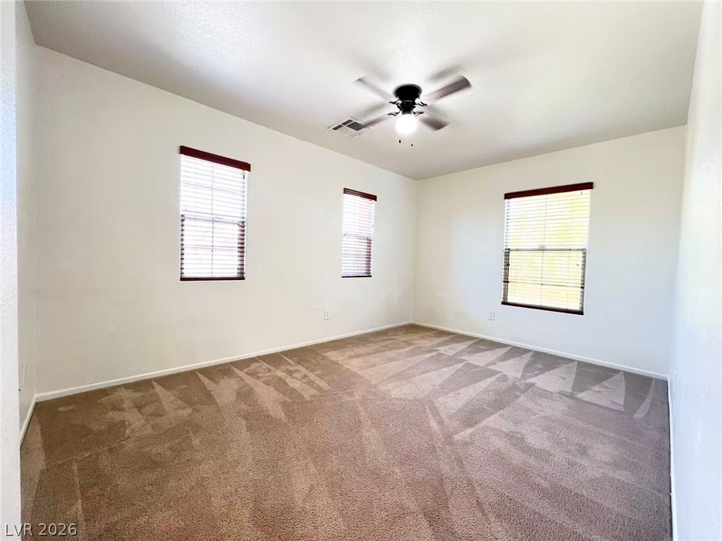 11143 Ranch Valley Street Las Vegas, NV 89179 - Photo 12 of 23 A quiet bedroom features a ceiling fan, plush carpeting, and multiple windows for abundant natural light.