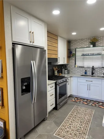 a kitchen with stainless steel appliances granite countertop a refrigerator a stove and a sink
