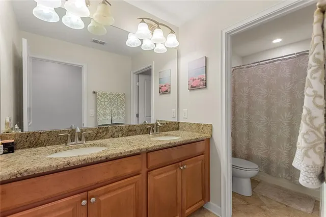 a bathroom with a granite countertop sink a toilet and a mirror