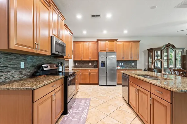 a kitchen with stainless steel appliances granite countertop a stove a sink dishwasher a refrigerator and cabinets with wooden floor