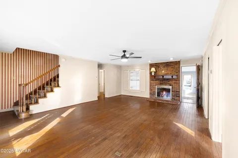 a view of empty room with fireplace and wooden floor