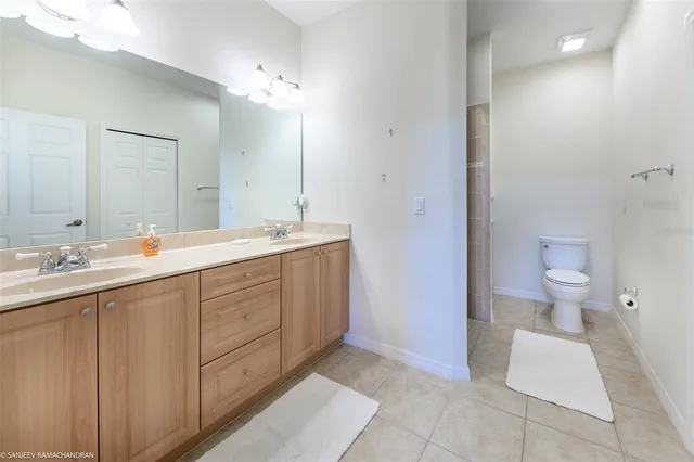 a spacious bathroom with a double vanity sink a mirror and a toilet
