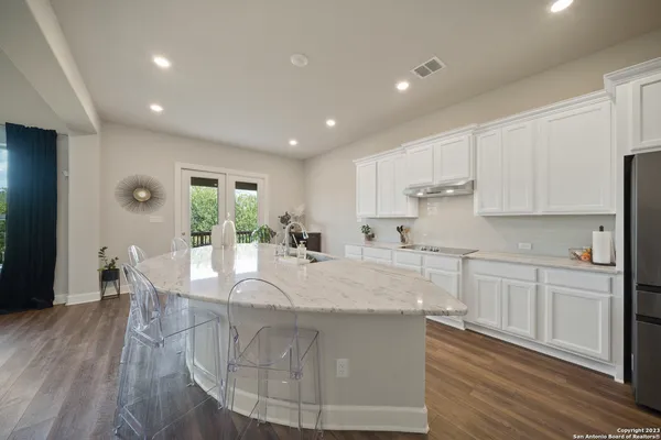 a large kitchen with kitchen island a island a sink a stove and wooden floors