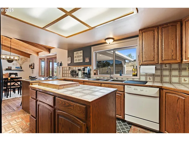 a kitchen with stainless steel appliances kitchen island granite countertop a refrigerator a stove and a sink with wooden cabinets