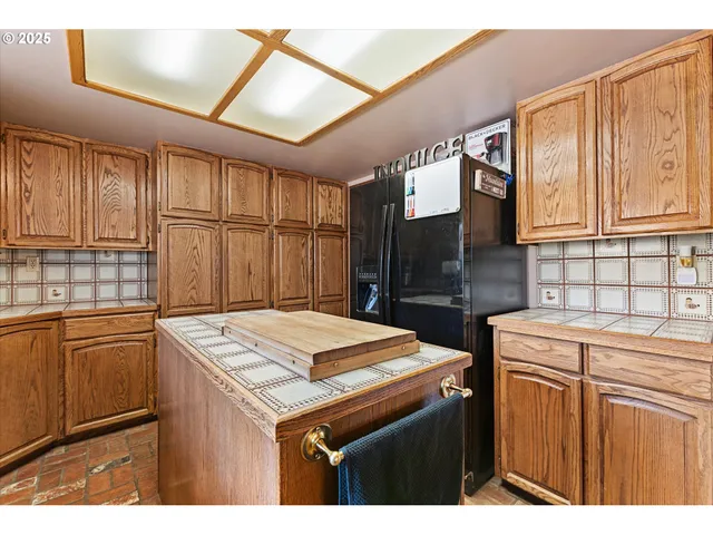 a kitchen with stainless steel appliances kitchen island granite countertop a refrigerator and a stove top oven