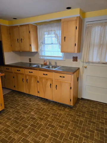a kitchen with granite countertop a sink a stove a cabinets and a window