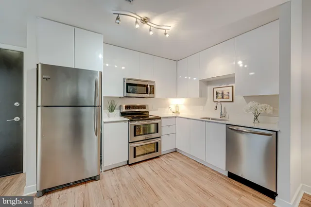 a kitchen with cabinets stainless steel appliances and wooden floor