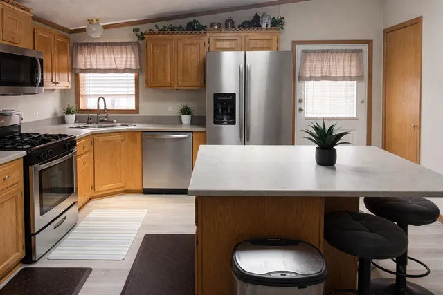 a kitchen with stainless steel appliances a dining table a stove a refrigerator and cabinets