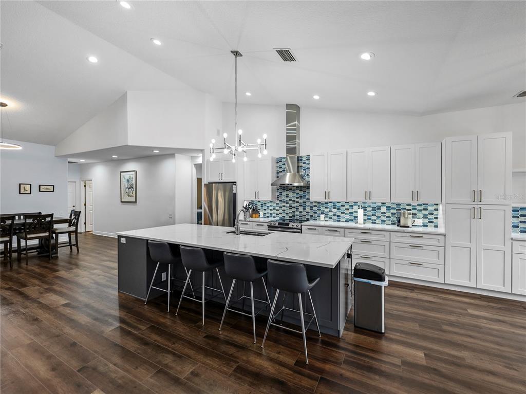34120 Americana Avenue Dade City, FL 33525 - Photo 16 of 71 a kitchen with stainless steel appliances granite countertop a table chairs stove and wooden floor
