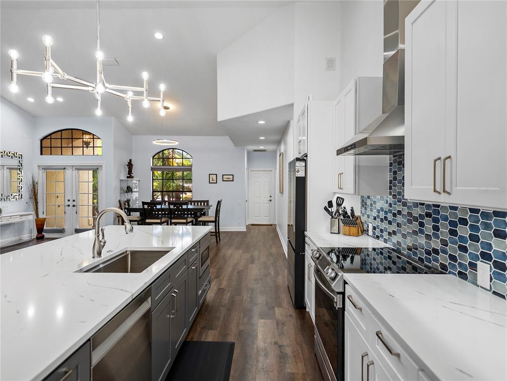 34120 Americana Avenue Dade City, FL 33525 - Photo 21 of 71 a large kitchen with stainless steel appliances kitchen island a large counter top a stove a chimney a sink and a center island