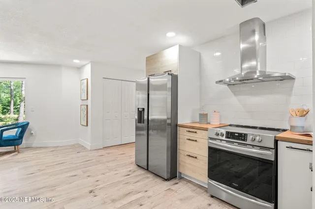 a kitchen with stainless steel appliances granite countertop a refrigerator a stove and a sink with wooden floor