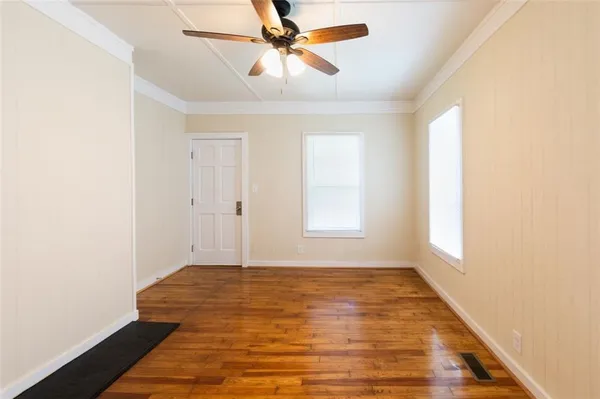 a view of empty room with wooden floor and fan