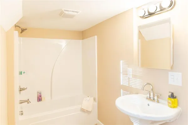a bathroom with a white bath tub sitting next to a white sink and a mirror