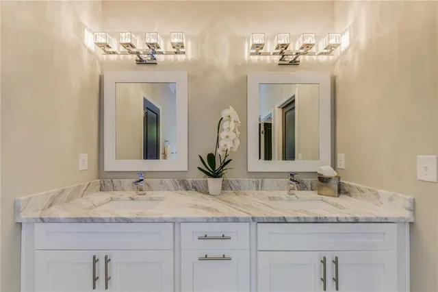 a bathroom with double vanity sinks granite vanity and a mirror