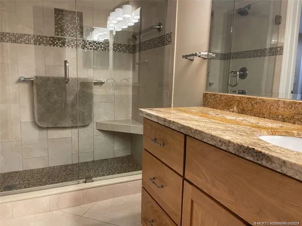 a bathroom with a granite countertop sink a mirror and shower