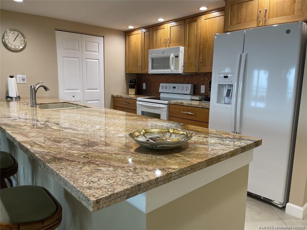 264 Northeast Edgewater Drive, Unit 102 Stuart, FL 34996 - Photo 5 of 16 a kitchen with stainless steel appliances granite countertop a sink oven and refrigerator
