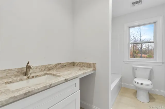 a bathroom with a granite countertop toilet sink and mirror