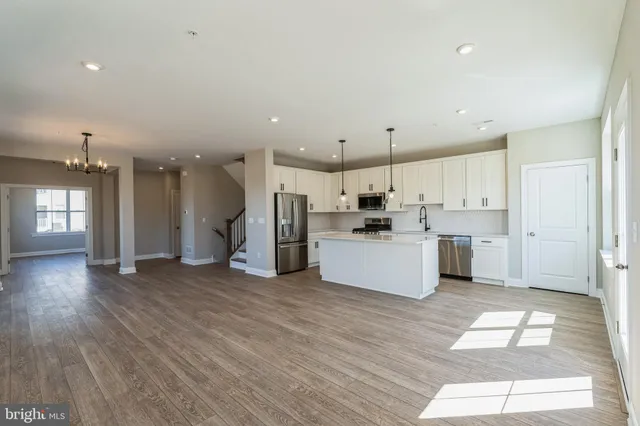 a large kitchen with a lot of white cabinets and stainless steel appliances