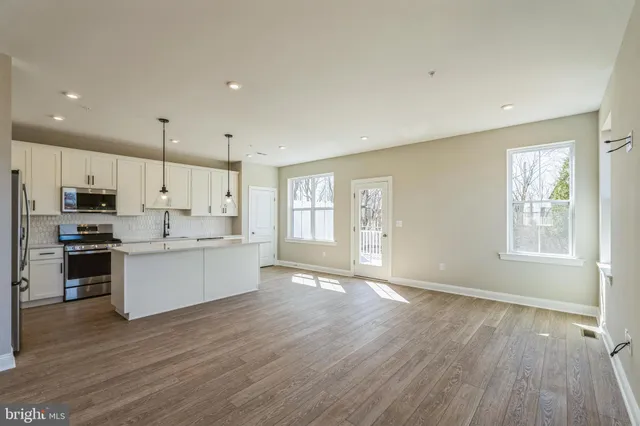 a large kitchen with stainless steel appliances granite countertop a stove a sink dishwasher and a large refrigerator with wooden floor