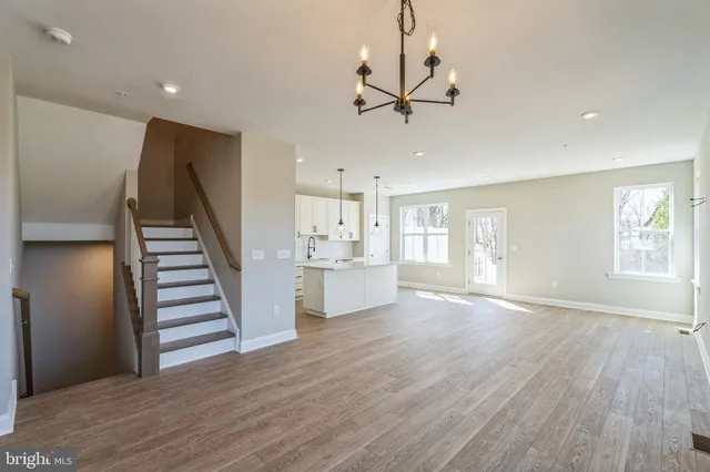a view of an empty room with wooden floor and stairs