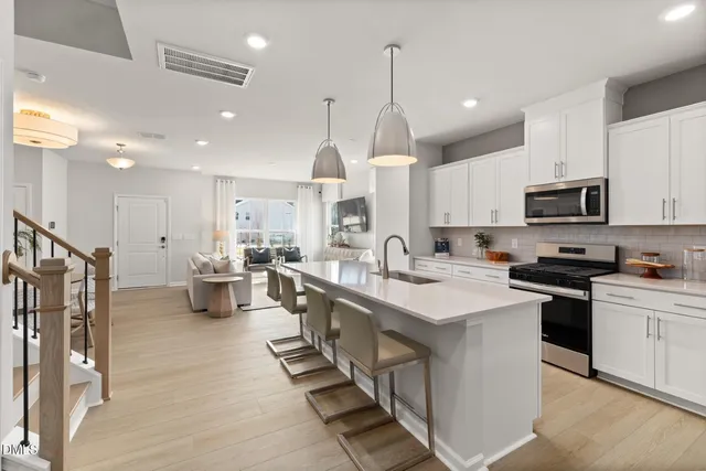 a kitchen with stainless steel appliances kitchen island granite countertop a sink a stove a refrigerator cabinets and chairs