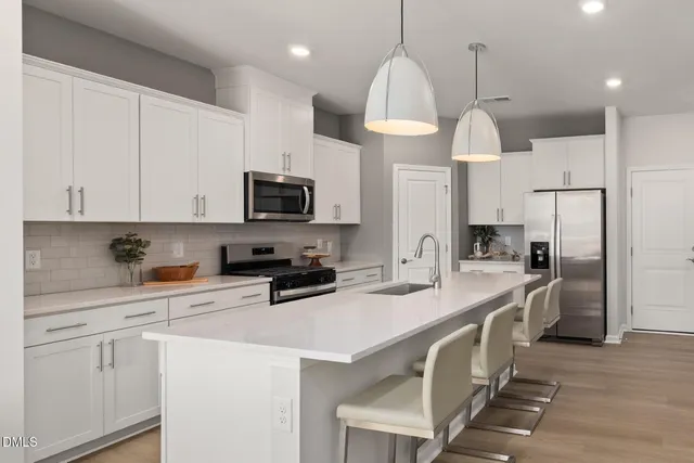 a kitchen with stainless steel appliances a sink a stove a refrigerator a center island and cabinets