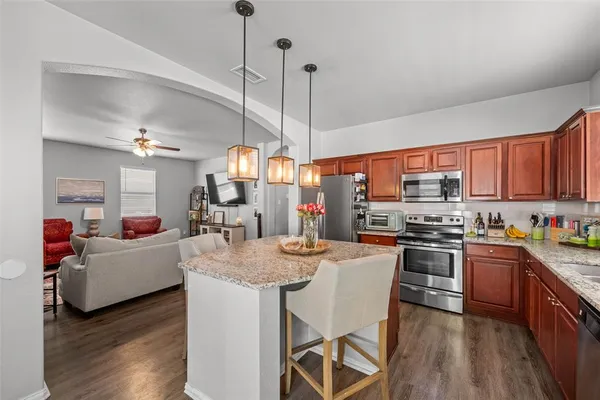 a kitchen with stainless steel appliances granite countertop a kitchen island hardwood floor sink stove dining table and chairs