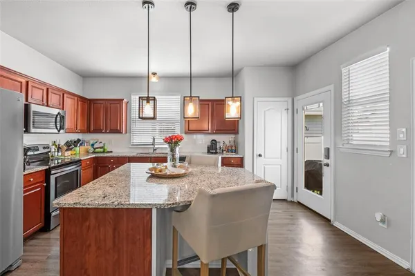 a kitchen with stainless steel appliances granite countertop a sink a stove and chairs