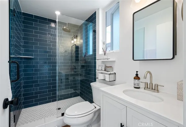 a bathroom with a toilet a sink a mirror and shower