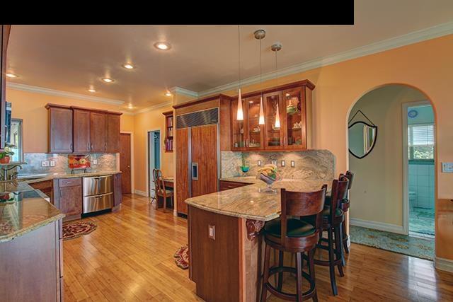a dining hall with stainless steel appliances kitchen island granite countertop a table chairs and a refrigerator