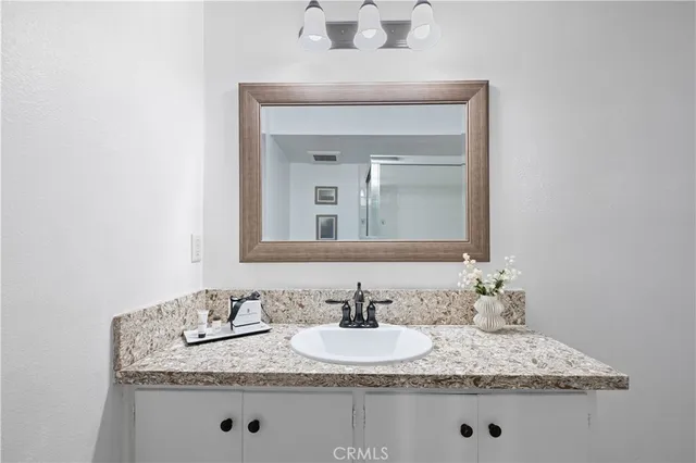 a bathroom with a granite countertop sink and a mirror
