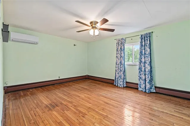 a view of an empty room with window and wooden floor