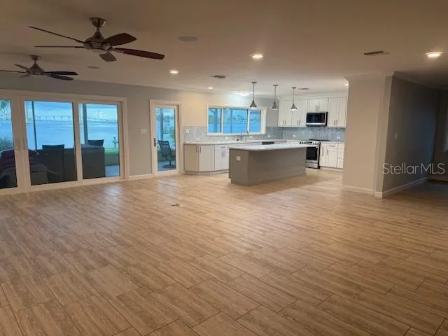 a view of large kitchen with kitchen island stainless steel appliances refrigerator stove microwave and cabinets