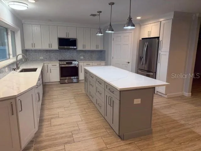 a kitchen with stainless steel appliances a stove top oven a sink a refrigerator and a center island