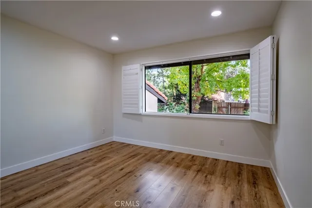 a view of empty room with wooden floor and fan
