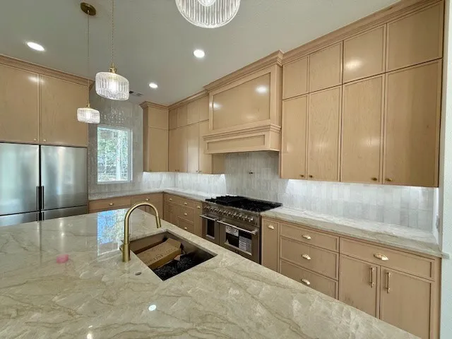a kitchen with granite countertop a stove a sink and a refrigerator