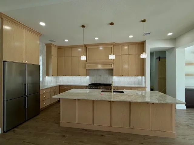 a kitchen with kitchen island granite countertop wooden cabinets and a refrigerator