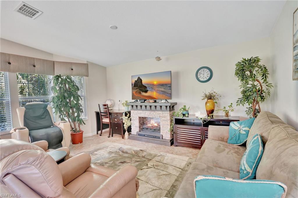 10709 Roseate Spoonbill Circle Estero, FL 33928 - Photo 4 of 32 a living room with furniture a fireplace a potted plant and a large window