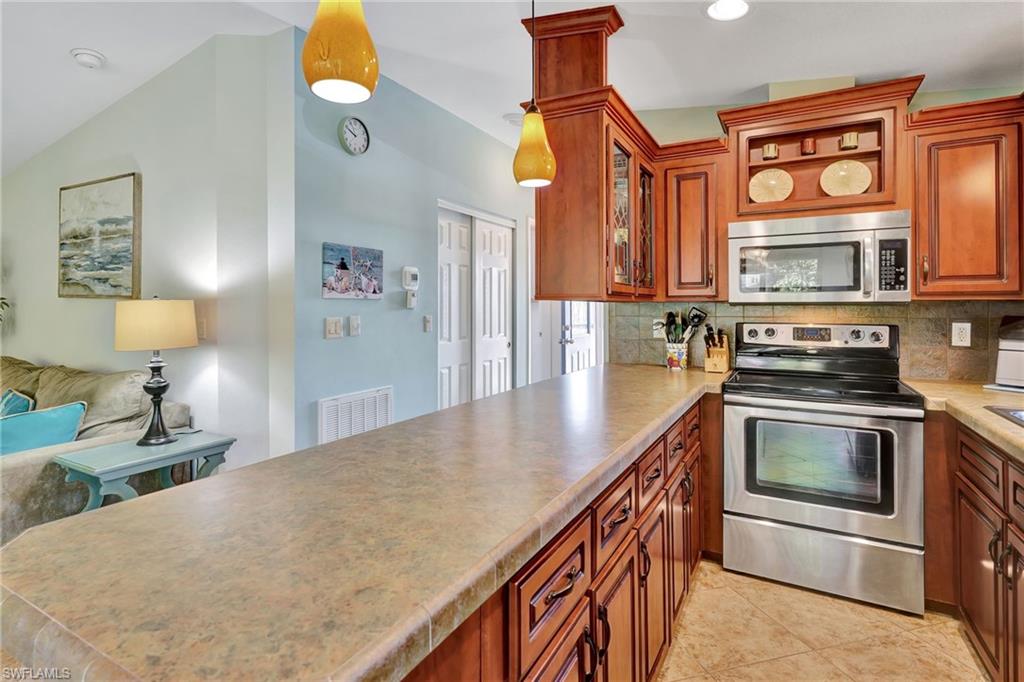 10709 Roseate Spoonbill Circle Estero, FL 33928 - Photo 9 of 32 a kitchen with stainless steel appliances a stove a sink and a microwave