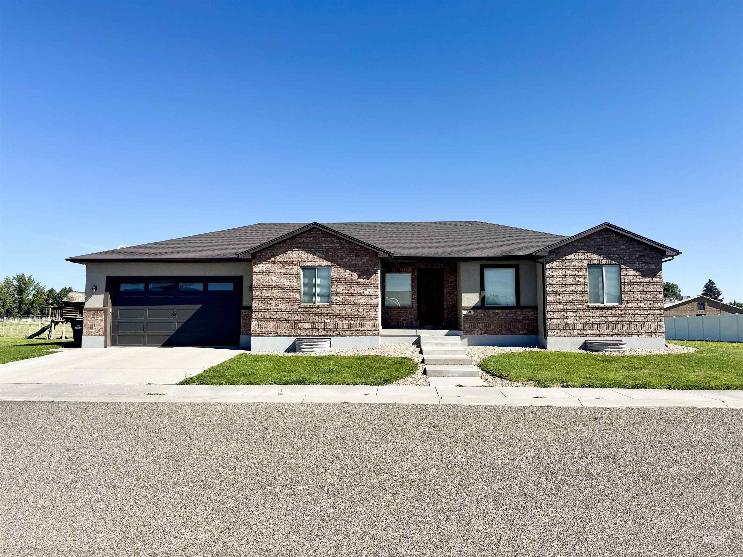 View of front facade featuring brick siding, driveway, and a garage
