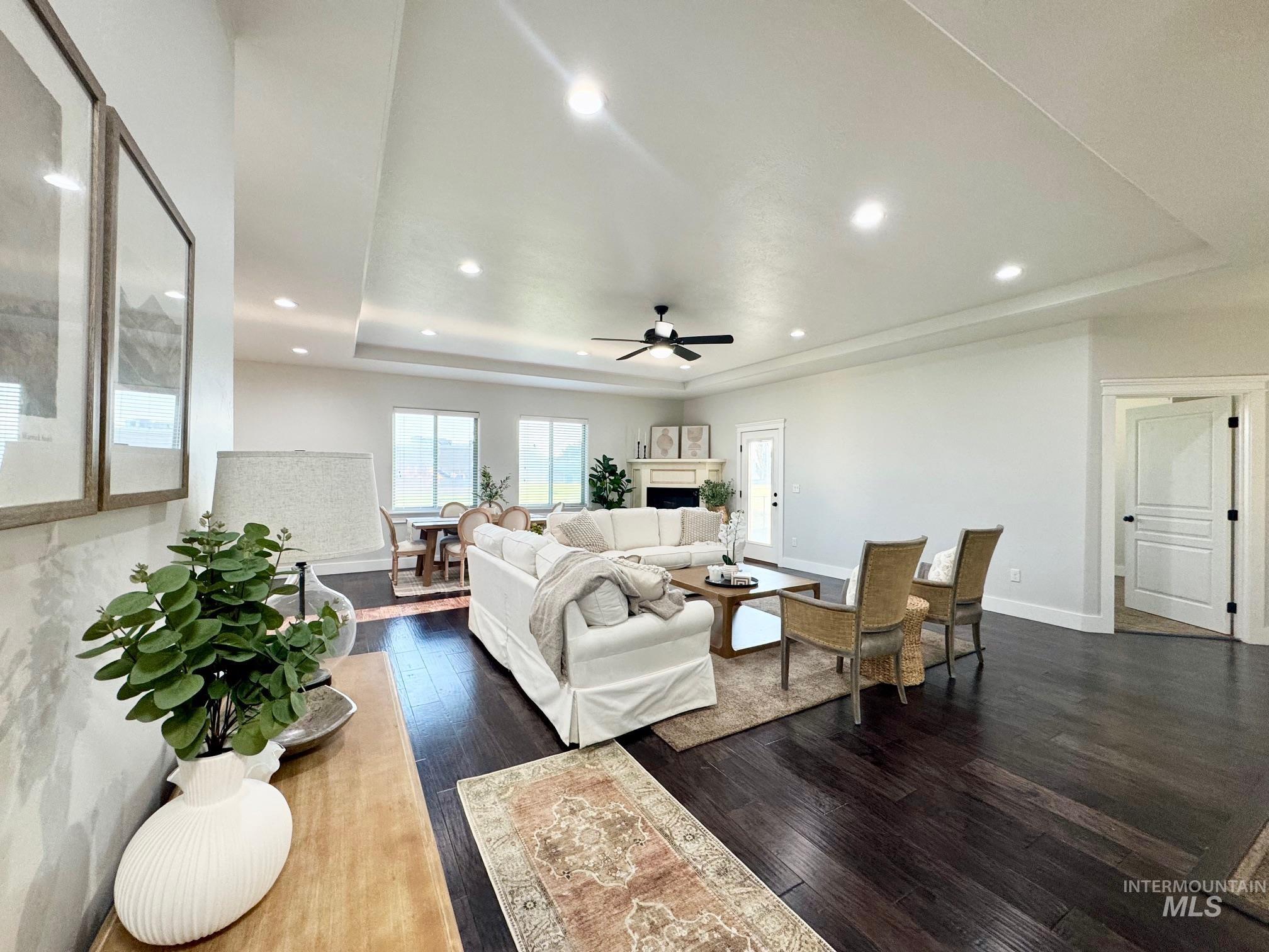 650 Lochsa Loop Heyburn, ID 83336 - Photo 4 of 26 Living area featuring a tray ceiling, dark wood-type flooring, recessed lighting, a fireplace, and ceiling fan